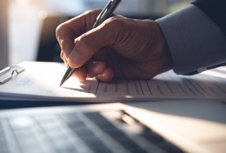 Close up of man completing a document. 