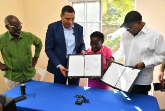 Prime Minister, the Most Hon. Andrew Holness (second left) and Norma Cooper, display the signed document for her one-bedroom unit in Lima, Adelphi, St. James, on January 8.  Also at the ceremony (from left) are Minister of Local Government and Community Development, Hon. Desmond McKenzie and Minister of Tourism and Member of Parliament for St. James East Central, Hon. Edmund Bartlett.


