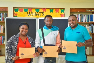 Member of Parliament for Clarendon North Central, Hon. Robert Morgan (right), and Customer Service Representative at the Registrar General’s Department (RGD), Shaniece Stewart (left), join Ackeem Manning in showing off his new birth certificate. Occasion was the presentation of birth certificates to 17 residents under ‘Operation Birthright’ during a recent ceremony at the Chapelton Library.