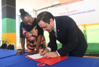 Minister of Culture, Gender, Entertainment and Sport, Hon. Olivia Grange (left), looks on as President of Special Olympics Europe, David Evangelista, signs a Memorandum of Understanding (MOU) between the Ministry and Special Olympics Jamaica in support of the Special Olympics Global Leadership Coalition for Inclusion. The symbolic signing ceremony was held on Wednesday (Jan. 17) at the Ministry, 4-6 Trafalgar Road in Kingston.

