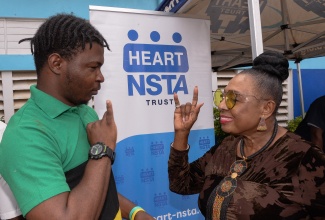 Minister of Culture, Gender, Entertainment and Sport, Hon. Olivia Grange, interacts with prospective HEART/NSTA Trust student, Michael Thomas, who is hearing-impaired, during the agency’s recruitment drive at Eltham Park Primary School in St. Catherine on January 28.