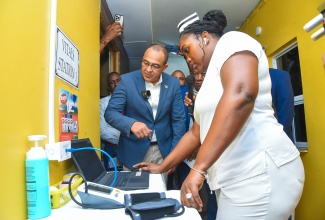 Minister of Health and Wellness, Dr. the Hon. Christopher Tufton (left), looks keenly at information generated by the Electronic Health Records (EHR) System, which has been implemented at the May Pen Hospital in Clarendon. The Minister is assisted by nurse in charge of the Outpatient Department at the hospital, Diana Reid West. Occasion was today’s (January 11) launch of the system at the hospital.