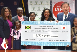 Minister of State in the Ministry of Education and Youth, Hon. Marsha Smith (third right), shares in the presentation of a cheque by the Embassy of Japan in Jamaica, to purchase a bus for Richmond Primary and Infant School in St. Mary. The provision of US$72,489 was facilitated through the Embassy under the Government of Japan’s Grassroots Human Security Grants Project. Sharing the moment (from left) are Executive Director, National Education Trust, Latoya Harris-Ghartey; student at the school, Ariana Cohen; Principal, Dwight Sanderson; Board Chair, Deloris Smith; Ambassador of Japan to Jamaica, His Excellency Yasuhiro Atsumi; and student Antwone Allen. The occasion was a grant signing ceremony at the Education Ministry in Kingston on Thursday (January 11). 