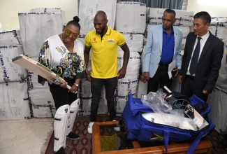 Culture, Gender, Entertainment and Sport Minister, Hon. Olivia Grange (left), gets the feel of a cricket bat during the handover of 90 sets of cricket kits by the Government of the Republic of India to the Jamaica Cricket Association (JCA) on January 4, at the Indian High Commission in Kingston. Observing (from left) are Captain of the Jamaica Cricket Team, Jermaine Blackwood;  President of the Jamaica Cricket Association (JCA), Billy Heaven, and Indian High Commissioner to Jamaica, His Excellency Rungsung Masakui.

