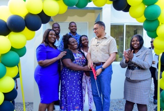 Prime Minister, the Most Hon. Andrew Holness (second right), cuts the ribbon to hand over a two-bedroom house to Gyllian Coleman (second left), in Berkshire Hall, St. Catherine, recently. Sharing the moment (from left) are Member of Parliament for St. Catherine North Eastern, Kerensia Morrison, and Chairperson for the Oversight Committee of the New Social Housing Programme (NSHP), Judith Robb Walters. Pictured in the background are family members of Mrs. Coleman.

