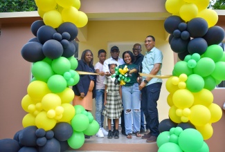 Prime Minister, the Most Hon. Andrew Holness (right), cuts the ribbon to hand over a three-bedroom unit under the New Social Housing Programme (NSHP) to Angelyn Miller (third from right) of Johns Hall, St. James, and her children on Monday, January 8. Sharing in the moment are (from left) Chairperson of the Oversight Committee of the NSHP, Judith Robb; Tourism Minister and Member of Parliament for St. James East Central, Hon. Edmund Bartlett; and Councillor for the Springmount Division, Uvel Graham.