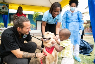 Little Leo Irving, who is a patient at the Bustamante Hospital for Children, pets therapy dog Dr. Teddy Barks, while Curator for the Hope Zoo, Joey Brown (left) and Ear, Nose and Throat (ENT) Consultant and Programme Coordinator for the Animal Assisted Recovery Care (AARC) Pilot Project at the hospital, Dr. Marsha James, look on. Observing in the background is Intensive Care Unit Nurse, Yohima Barban Lao.

