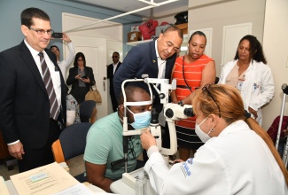 Health and Wellness Minister, Dr. the Hon. Christopher Tufton (standing, second left); and Cuba’s Ambassador to Jamaica, His Excellency Fermîn Gabriel Quiñones Sanchéz (left), observe as Cuban Ophthalmologist, Mauritza Perez Blanco, administers an eye test on patient George Scott. Occasion was a tour of the St. Joseph’s Hospital in St. Andrew on February 6, which is one of two public health facilities where the Jamaica-Cuba Eye Care Programme operates. The other is the Kingston Public Hospital. Also looking on are Coordinator for the Jamaica-Cuba Eye Care Programme, Natasha Biggs (second right); and Cuban Ophthalmologist, Mayra Chaveco Almanza.

