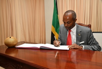 Permanent Secretary in the Office of the Prime Minister, Ambassador Dr. Rocky Meade, signs the condolence book for late Justice Dennis Morrison, at the Office of the Prime Minister (OPM) on Tuesday (February 20).