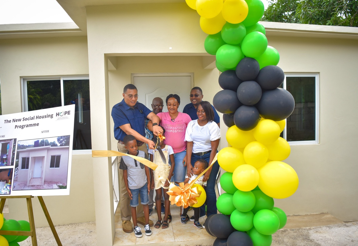 Prime Minister, the Most Hon. Andrew Holness (left), cuts the ribbon at the recent handover of a two-bedroom house to Kayla Hylton (centre), a resident of Rock River in Clarendon North Central, while Permanent Secretary in the Ministry of Economic Growth and Job Creation, Arlene Williams (right), looks on. Also sharing the moment (from left, back row) are Councillor for the Rock River Division, Uriah Mitchell, and Member of Parliament for the area, Hon. Robert Morgan.

