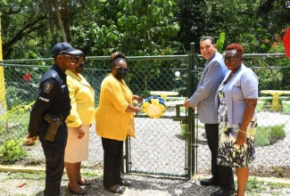 Minister of State in the Office of the Prime Minister, Hon. Homer Davis (second right), and Senior Manager for Social Development at the Jamaica Social Investment Fund (JSIF), Mona Sue Ho (centre), cut the ribbon to open a green space at Lethe Primary and Infant schools in St. James in July 2022, under the Integrated Community Development Project (ICDP) II. Looking on (from left) are Superintendent in Charge of Operations, St. James Police Division, Eron Samuels; Regional Director at the Ministry of Education and Youth, Dr. Michelle Pinnock; and Principal of Lethe Primary and Infant School, Allison McGhie.

