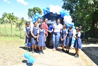 Principal of Mount Ward Primary School in Hanover (second left), Paula Chambers-Morris, accepts the donation of a 1,000-gallon water-storage tank from Marketing Officer for Courts Ready Cash, Kiara Henny (right), at the school on Thursday (February 15). Sharing the moment are Senior Education Officer at the Ministry of Education and Youth, Region Four, Jacqueline Gardiner, and students of the school.

