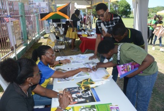 Jamaica Information Service (JIS) Public Relations Officer (PRO), Judith Hunter (left), and Acting Special Projects Manager, Charnele Henry (second left), interact with students during the Jamaica Day National Civic Ceremony at William Knibb Memorial High School in Trelawny, on February 23.