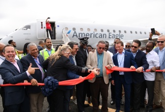 Minister of Science, Energy, Telecommunications and Transport, Hon. Daryl Vaz (fifth right), cuts the ribbon to mark the arrival of the inaugural American Airlines flight from Miami to the Ian Fleming International Airport in Boscobel, St Mary, on Saturday (February 24). He is joined by President and Chief Executive Officer of the Airports Authority of Jamaica, Audley Deidrick (second left); Jamaican-born flight captain, Marc Coley (fifth left); Executive Chairman of Sandals Resorts International, Adam Stewart (fourth right); and United States Ambassador to Jamaica, Nick Perry (second right).