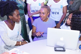 Minister of Education and Youth, Hon. Fayval Williams (centre), engages with young women participating in a hackathon competition. 