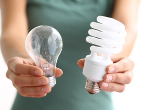 Hands holding traditional and energy efficient light bulbs. 
