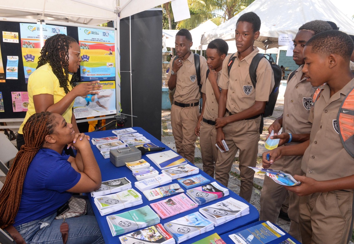 Students at St. Catherine High School listen attentively while Acting Special Projects Manager, Jamaica Information Service (JIS), Charnele Henry (second right), shares information about the agency and the JIS publications on display. Looking on is Special Projects Officer, JIS, Romona Geohaghan (seated left). Students and adults visited the JIS booth to receive information on healthy eating, citizen rights, breast cancer, road safety, and other subject matters at the school’s health fair on Friday, March 15. Visitors to the booth were also able to interact with Writer/Producer/Presenter, JIS Radio, Jayda Francis, and test their skills at voice acting.

