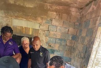 State Minster in the Ministry of Labour and Social Security, Dr. the Hon. Norman Dunn (right), assembles the Rollator Walker, during the handover of items to Murinne Steer (left) for her disabled son, at Liberty Valley in Brown’s Town, St. Ann, on February 20.  Others looking on (from second left) are Divisional Director for Social Security in the Ministry, Suzette Morris; Corporate Communications Manager, Marcia Williams; and Parish Administrator for the Ministry’s St. Ann office, Ansel Rob.

