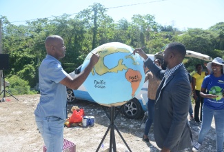 Regional Operations Manager of WPM Waste Management Limited, Edward Muir (left), and Mayor of Montego Bay, Richard Vernon, putting the final touches to an eco-sculpture during a plastic bottle collection drive in Estuary, St. James, to mark Global Recycling Day, on Monday, March 18.