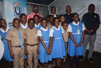 Chief Executive Officer of the Universal Service Fund (USF), Dr. Daniel Dawes (background, second left), joins students of Siloah Primary School and other stakeholders at the launch of Community Wi-Fi in Siloah, St. Elizabeth on Wednesday, March 20.  From left (in background) are Principal of the school, O’Neil Larmond; Sergeant of the Siloah Police Station, Ronnie Wallace; and Parish Manager of the Social Development Commission (SDC), Alric Miller. 