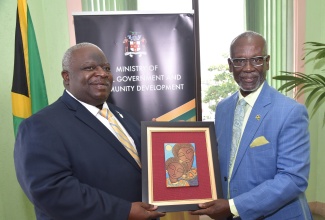 Minister of Local Government and Community Development, Hon. Desmond McKenzie (right), presents Bahamian Minister of State in the Office of the Prime Minister, Hon. Leon Lundy, with a locally made art piece, during a courtesy call at the Ministry’s offices in Kingston on Tuesday, March 12.