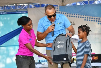 Minister of Health and Wellness, Dr. the Hon. Christopher Tufton (centre), presents a knapsack to little Savannah Wright (right) for her participation in the St. Thomas instalment of the Ministry’s ‘Know Your Numbers’ tour. The event was held at the Rudloph Elder Park in Morant Bay on Thursday (March 14).

