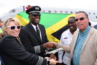 Minister of Science, Energy, Telecommunications and Transport, Hon. Daryl Vaz (right), receives a replica of an American Airlines (AA) aircraft from Jamaican-born pilot Captain Marc Coley (second left), who was in charge of the airline’s inaugural flight into the Ian Fleming International Airport in St. Mary on February 24. Sharing the moment is First Officer, Christy Schafer (left), while Member of Parliament for St. Mary Western, Robert Montague (second left), looks on.

