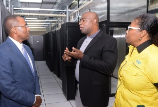 Minister of Finance and the Public Service, Dr. the Hon. Nigel Clarke (left), is updated on developments regarding the upgraded eGov Data Centre in Kingston by eGov Jamaica Limited’s Senior Director for Operations and Support Services, Devon Sterling, during a tour of the facility on Thursday (February 29). Also listening is Executive Director, Transformation Implementation Unit (TIU), Maria Thompson Walters.

