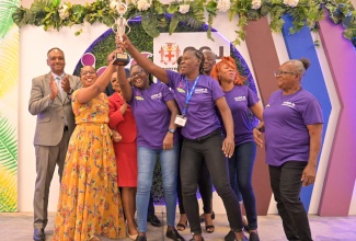 Managing Director of the Jamaica Social Investment Fund (JSIF), Omar Sweeney (background left), applauds the top placed environmental wardens from the community of Anchovy, in St. James, during a certification ceremony held on March 28, at the AC Mariott Hotel, in New Kingston.