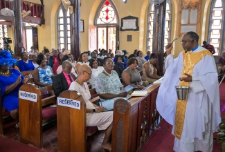 Minister of Education and Youth, Hon. Fayval Williams (seated left) is sprinkled with holy water by Rector, Mandeville Parish Church, Rev. Michael Elliott at the Jamaica Teachers’ Association’s 60th Anniversary Church Service held at the church in Manchester today (March 31).

 