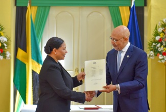 Governor-General, His Excellency the Most Hon. Sir Patrick Allen (right), presents newly appointed Custos Rotulorum for the parish of Clarendon, Edith Chin, with the Instrument of Office, during the swearing-in ceremony at King’s House on March 1.