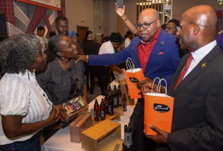 Minister of Tourism, Hon. Edmund Bartlett (second right), and Minister of Industry, Investment and Commerce, Senator the Hon. Aubyn Hill (right), interact with co-owners of Irie Gourmand, Andrea (second left) and Colleen Sybblis during the opening of last year