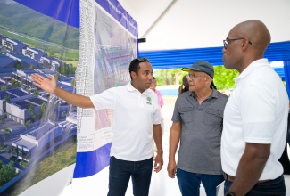 General Manager, Urban Development Corporation (UDC), Robert Honeyghan (left), outlines details of the Raintree Commercial Complex to Entrepreneur, Hugh Coore (centre), at the Raintree Commercial Complex Open House at Caymanas Estate in Ferry Pen, St. Catherine, on Saturday (April 27). Listening is Deputy General Manager, Subsidiary Management and Revenue Generation, UDC, Sherlock Glenister.