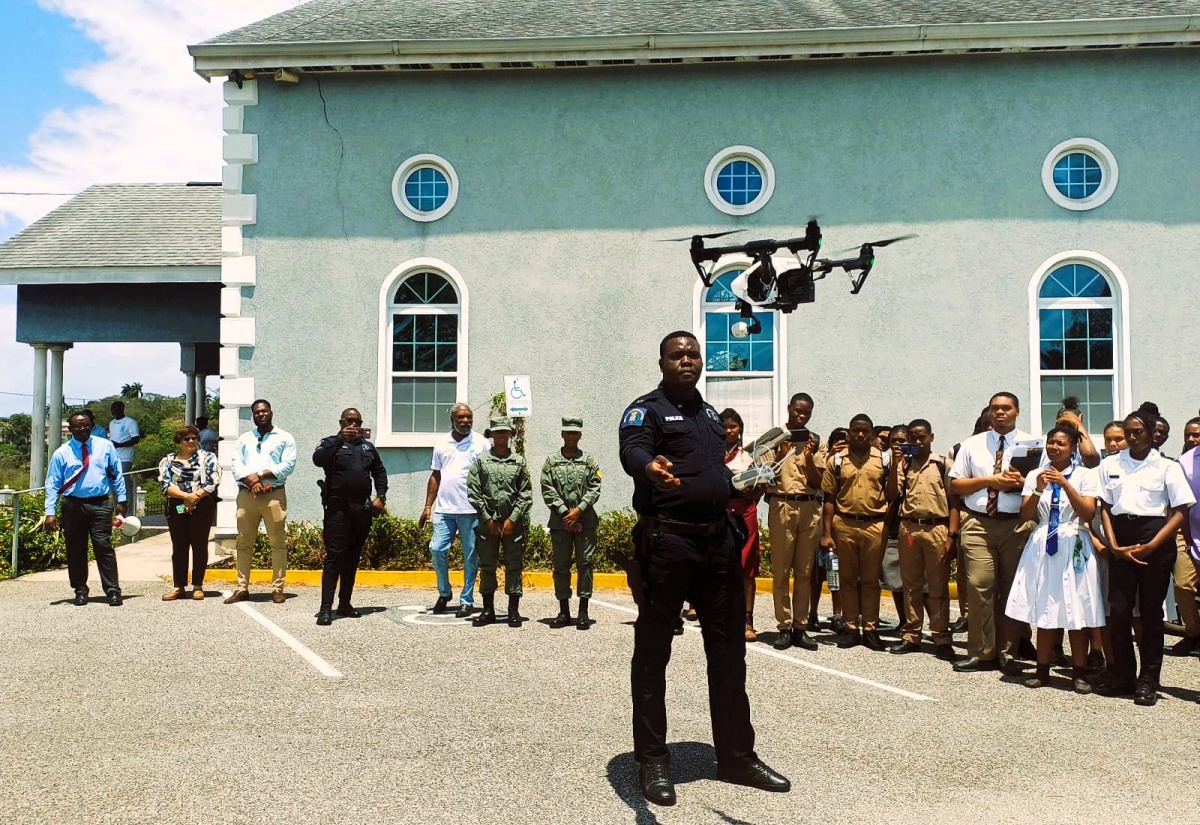Member of the Specialised Operations Unit, Jamaica Constabulary Force (JCF), Constable Simba Anderson (foreground), demonstrates the operation and functions of a drone to students from schools across St. James and other stakeholders. The occasion was the recent launch of a drone training programme spearheaded by the Cornwall College Old Boys’ Association Mid-Atlantic Chapter in the United States and the Sandals Foundation. The training will be led by the JCF, Jamaica Defence Force (JDF) and Jamaica Fire Brigade (JFB).

