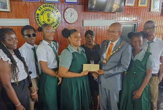Mayor of Spanish Town, Councillor Norman Scott (third right), presents a check valued at $300,000 to Captain of the St. Jago High School 2024 Schools’ Challenge Quiz team, Jhaneille Esson, at Thursday’s (April 11) monthly meeting of the St. Catherine Municipal Corporation in Spanish Town. Assistant coach, Chevelle Crosdale-Lee (left) and other members of the team share the occasion. St. Jago defeated Calabar High School with a score of 37-33 in the competition finals held on April 5 to claim the coveted title for the third straight year.