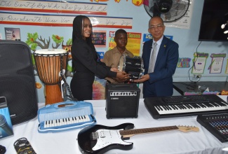 National Security Minister, Hon. Dr. Horace Chang (right), presents a drum to Acting Vice Principal, Kingston High School, Sashauna Gordon (left) and grade-seven student, Kimani Davis. Occasion was the handover of musical instruments, valued at over $1 million, by the Ministry through its Music, Sports, and Technology (MST) Initiative, at the school’s location at 172 King Street on Tuesday (April 9).