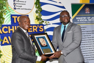 Minister of Labour and Social Security, Hon. Pearnel Charles Jr., (left), presents Jordon Freeman with the 2024 Programme of Advancement through Health and Education (PATH) Trailblazer Award, during the PATH Top Achiever’s Awards Ceremony at the Spanish Court Hotel in New Kingston on April 11.

