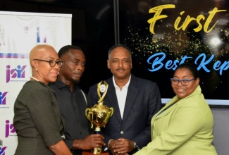 Minister of Education and Youth, Hon. Fayval Williams (left), presents the Best Kept School trophy to Groundsman at Edward Seaga Primary School, Donovan Moulton (second left). The presentation was made during the Jamaica Social Investment Fund’s (JSIF) Best Kept School Competition awards ceremony at JSIF’s office in Kingston on Friday (April 5). Also participating are: JSIF Managing Director, Omar Sweeney (second right), and Principal of the school, Shernet Clarke Tomlinson.

