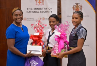 Minister of State in the Ministry of National Security, Hon Juliet Cuthbert Flynn (left), presents tablets and gift baskets to St. Elizabeth Technical High School (STETHS) students Damille Williston (centre) and Lyshaniya Elson during the awards ceremony for the inaugural ‘SheSecures Jamaica’ National Cybersecurity Competition held on April 18 at Jamaica House. STETHS scored the highest points in the secondary school category of the competition.