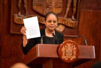 Minister of Legal and Constitutional Affairs, Hon. Marlene Malahoo Forte, displays a copy of the Bill to amend Section 61 of the Constitution of Jamaica to formulate new Words of Enactment, while speaking during a recent post-Cabinet press briefing at Jamaica House.

