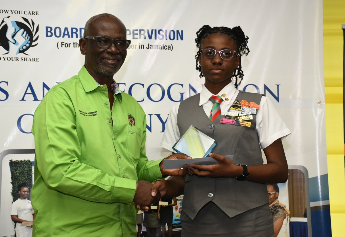 Minister of Local Government and Community Development, Hon. Desmond McKenzie (left), makes a presentation to Mickeisha Golding for outstanding achievement, during the Board of Supervision's annual awards ceremony held recently at Boone Hall Oasis, St. Andrew. A total of 61 students were awarded for excellent performance in the Primary Exit Profile (PEP), Caribbean Advanced Proficiency Examination (CAPE) and CSEC in 2023. Mickeisha, who is a student of Montego Bay High, received the Top Achiever Award for CSEC.