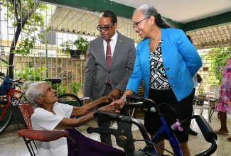 State Minister in the Ministry of Labour and Social Security, Dr. the Hon Norman Dunn and Permanent Secretary in the Ministry, Colette Roberts Risden (right), greet 101-year-old Adlin Sang (left), during a visit to her home on Rudolph Burke Avenue, Kingston 20, on Monday (May 20), as part of activities in observance of Centenarians’ Day.