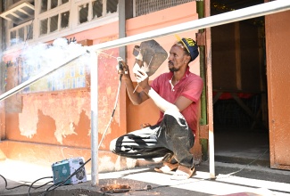 Welder, Peter Simpson, adds the finishing touches to a railing to support ramp access at Park Mountain Primary and Infant School in St. Elizabeth during Labour Day activities at the institution, which was the Parish Project, on Thursday (May 23).