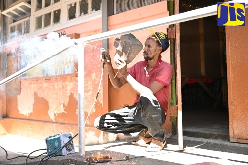 Welder, Peter Simpson, adds the finishing touches to a railing to support ramp access at Park Mountain Primary and Infant School in St. Elizabeth during Labour Day activities at the institution, which was the Parish Project, on Thursday (May 23).