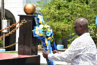 Minister of Local Government and Community Development, Hon. Desmond McKenzie, places a floral tribute at the Secret Gardens monument, which bears the names of children, who have lost their lives under tragic and violent circumstances. Occasion was the Kingston and St. Andrew Municipal Corporation’s  (KSAMC) Child Month ceremony held at the monument, downtown Kingston on Sunday (May 5).