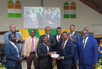 Mayor of Montego Bay, Councillor Richard Vernon (front row, second left), hands a contribution to Senior Pastor at the Montego Bay New Testament Church, Bishop Ruel Robinson (third left), for the church’s charity fund, on behalf of the St. James Municipal Corporation. With them are  Councillors from the municipality. Occasion was a Workers’ Week/Labour Day Thanksgiving Service, held at the church on Sunday (May 19).

