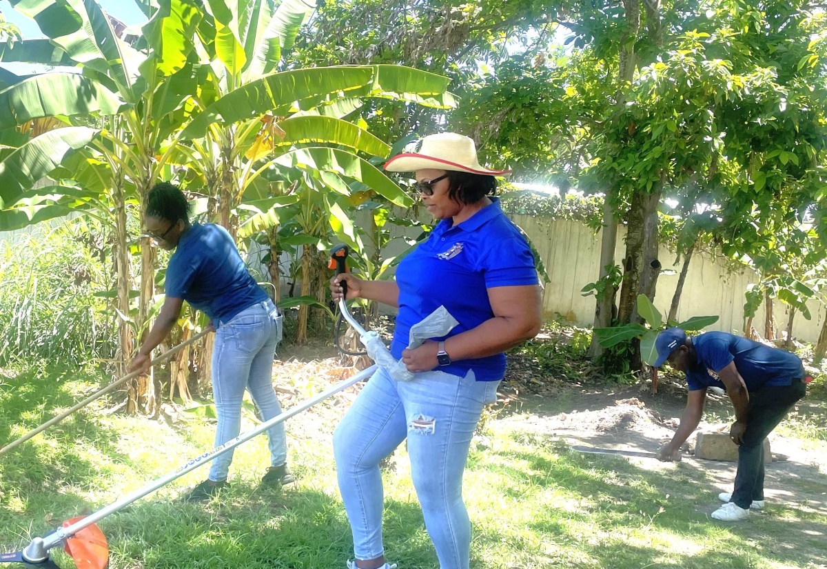 Team members of the Hanover Parish Court join forces with members of the Jamaica Constabulary Force (JCF) in cleaning the courtyard on Labour Day, Thursday, May 23.