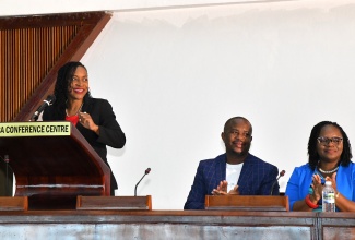 State Minister in the Ministry of Education and Youth, Hon. Marsha Smith, delivers her address at the Child Protection and Family Services Agency (CPFSA) Annual General Staff Meeting held on Wednesday (April 24) at Jamaica Conference Centre, downtown Kingston. Listening are Manager of the Windsor Childcare Facility in St. Ann, Wayne Grant (centre), and Placement Coordinator at the CPFSA, Taneka Cassanova-Durrant.

