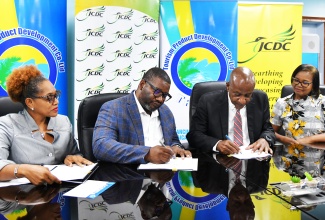 Executive Director, Tourism Product Development Company Limited (TPDCo), Wade Mars (second left) and Executive Director, Jamaica Cultural Development Commission (JCDC), Lenford Salmon (second right), sign a Memorandum of Understanding (MOU) to enhance cultural and tourism training for contestants in the Miss Jamaica Festival Queen competition, at the offices of the TPDCo, on May 30. Witnessing the signing (from left) are Company Secretary, TPDCo, Rosie Carty, and Director, Community Cultural Development Services Division, JCDC, Marjorie Leyden-Kirton.