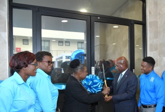 Minister of Culture, Gender, Entertainment and Sport, and Member of Parliament for St. Catherine Central, Hon. Olivia Grange (centre) and Industry, Investment and Commerce Minister, Senator the Hon. Aubyn Hill (second right), cut the ribbon to open the new R.A. Williams Distributors Limited facility in the New Brunswick Village in St. Catherine, recently. Observing (from left) are Chief Operations Officer, R.A. Williams Distributors Limited, Jewel Reid; Founder and Chief Quality Officer, Evelyn Williams; and Chief Executive Officer, Audley Reid.

